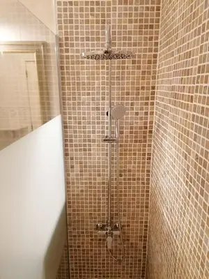 a shower in a bathroom with brown tiled walls at Porque Você Merece in Quarteira