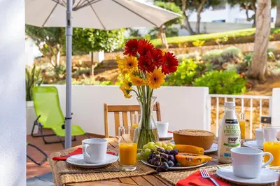 a table with a vase of flowers and fruit on it at Apartamento Yacintos in Albufeira