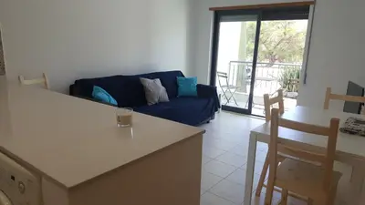a living room with a blue couch and a table at Vista das Ondas Apartment in Albufeira