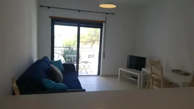 a living room with a blue couch and a sliding glass door at Vista das Ondas Apartment in Albufeira