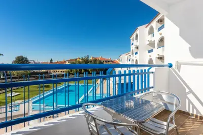 a balcony with a table and chairs next to a swimming pool at Tropical Sol in Albufeira