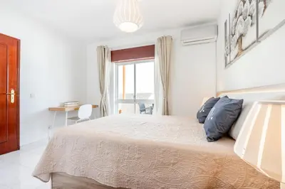 a white bedroom with a large bed and a window at My Place @ Faro Ria Views in Faro