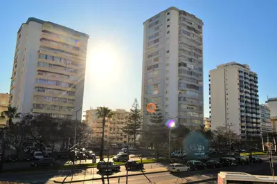 two tall buildings with cars parked in a city at Torres Mira Praia by Garvetur in Quarteira