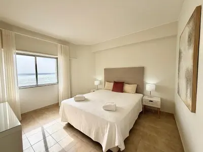 a bedroom with a large bed and a large window at Torres Mira Praia by Garvetur in Quarteira