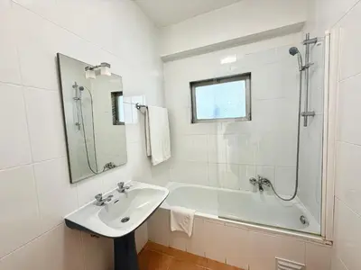 a white bathroom with a sink and a tub at Torres Mira Praia by Garvetur in Quarteira