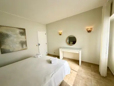 a bedroom with a bed and a table and a mirror at Torres Mira Praia by Garvetur in Quarteira