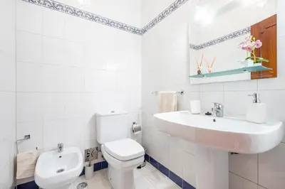 a white bathroom with a toilet and a sink at My Place @ Faro Duplex in Faro