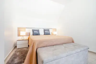 a white bedroom with a bed and a couch at My Place @ Faro Duplex in Faro