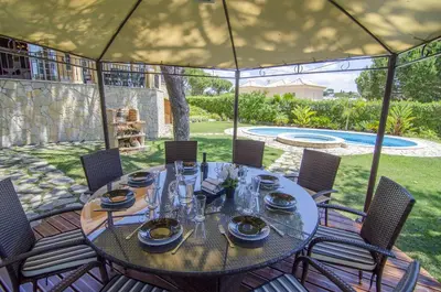 a table in a tent with chairs and a pool at Villa Lira in Almancil