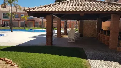 a pavilion with a table and a chair next to a pool at Villa Jardins 2 by Sunny Deluxe in Albufeira