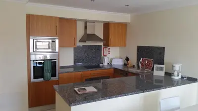 a kitchen with granite counter tops and wooden cabinets at Vista das Ondas Olhos de Agua in Albufeira