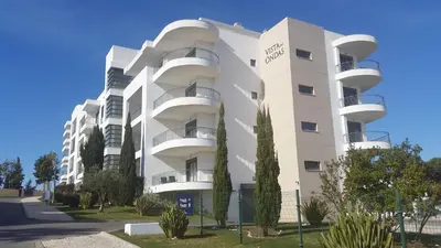a white apartment building with trees in front of it at Vista das Ondas Olhos de Agua in Albufeira