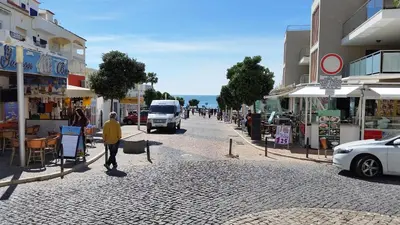 a man walking down a street with a white van at Vista das Ondas Olhos de Agua in Albufeira