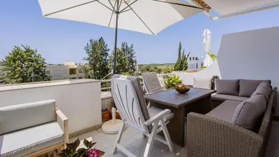a patio with a table and chairs and an umbrella at T1 Grevilias em Vilamoura - Greice Homes in Quarteira