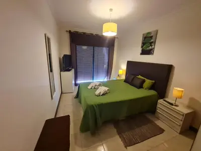 a bedroom with a green bed and a window at Quarteira T1 - Oceanides in Quarteira