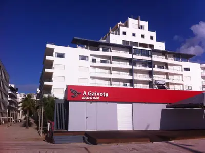 a large white building with a red sign on it at Quarteira T1 - Oceanides in Quarteira