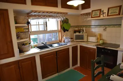 a kitchen with wooden cabinets and a sink and a window at Faro Beach House in Faro
