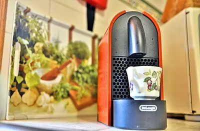 a close up of a red and black appliance with a cup in it at Faro Beach House in Faro