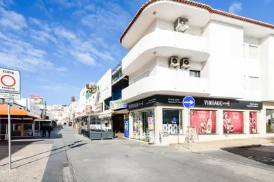 a white building with shops on a city street at Casas Barulho Penthouse Old Town in Albufeira