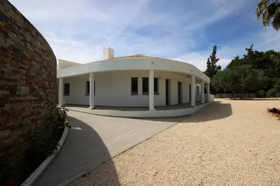 a large white house with a brick wall at L&F House in Algoz