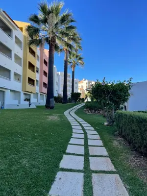 a walkway in a park with palm trees at Belavista Apartment in Albufeira
