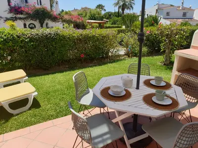 a table with chairs and an umbrella in a yard at T2 Apartment Old Village Vilamoura in Vilamoura