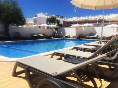 a swimming pool with lounge chairs and an umbrella at Areias Senses in Albufeira