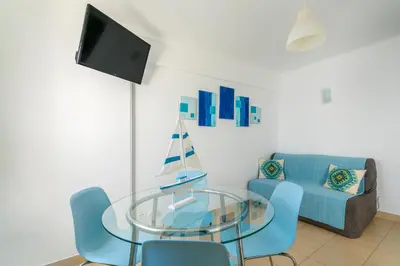 a living room with a glass table and a blue couch at Apartamento Mar in Quarteira