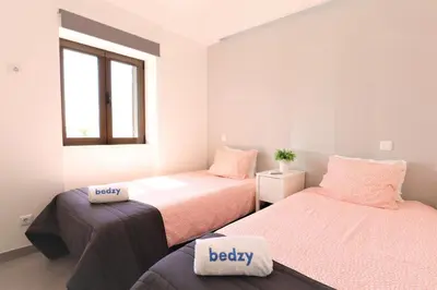 a bedroom with two beds with pink sheets and a window at Vila - Mar - Private outdoor Jacuzzi - wifi & airco - by bedzy in Albufeira