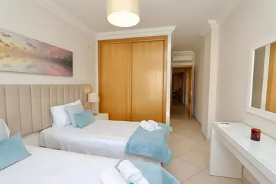 a bedroom with a white bed with blue pillows at Praia Village 104 - Clever Details in Vilamoura
