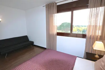 a bedroom with a bed and a window with a couch at Monte Laguna - Clever Details in Vilamoura