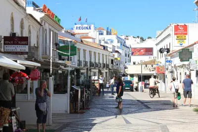 a group of people walking down a street with buildings at Apartamentos Colina do Mar Downtown Albufeira in Albufeira