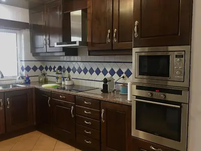 a kitchen with wooden cabinets and stainless steel appliances at Casa das Figuras in Faro
