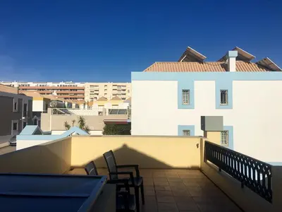 a balcony with two chairs and a building at Casa das Figuras in Faro