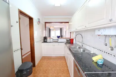 a kitchen with white cabinets and a black counter top at Pinhal do Golf - Clever Details in Vilamoura
