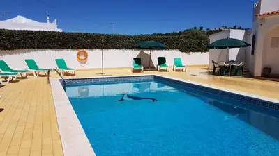 a swimming pool with blue lounge chairs and a pool at Vila Ricardo by Sunny Deluxe in Albufeira
