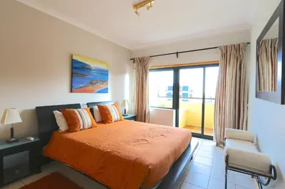 a bedroom with a large bed and a balcony at Terraços de Vilamoura 55- Clever Details in Vilamoura