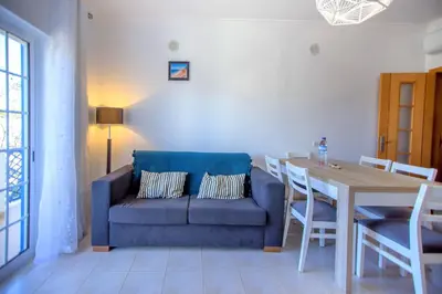 a living room with a blue couch and a table at Olhos de Água Apartment Albufeira II in Albufeira
