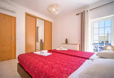 a bedroom with two beds with red sheets and a window at Olhos de Água Apartment Albufeira II in Albufeira