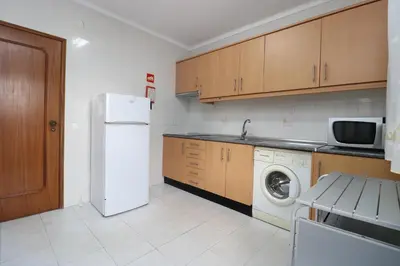 a kitchen with a white refrigerator and a washing machine at Villa Estela in Albufeira