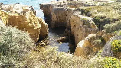 a cave in the rocks next to the water at Villa Lena in Albufeira