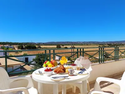 a table with a plate of food on a balcony at Falesia Beach Apartment by Be Cherish in Roja- Pé