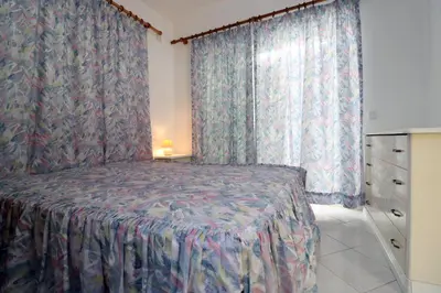a bedroom with a bed and a window with curtains at Villa Gonçalves in Albufeira