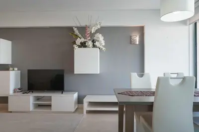 a living room with a television and a table with a vase of flowers at Aquamar 416 by Vilamoura Sun - espaçoso, in Vilamoura