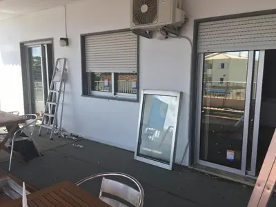 a room with windows and a fan and a ladder at Guest House Oliveira in Boliqueime