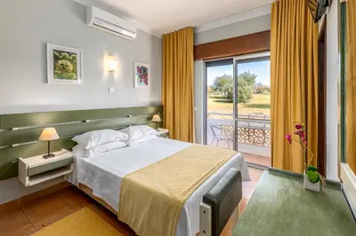a hotel room with a bed and a balcony at Guest House Oliveira in Boliqueime