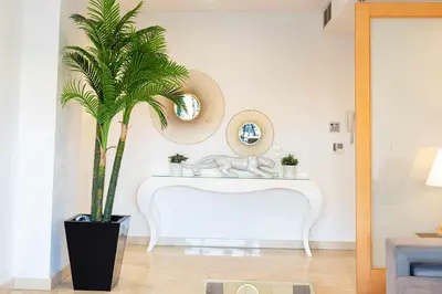 a living room with a white table and a palm tree at Marina Vilamoura - Aquamar 013 - By VilamouraSun in Vilamoura