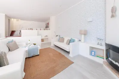 a white living room with white furniture and a staircase at Vila dos Lírios - Blue Sea in Albufeira