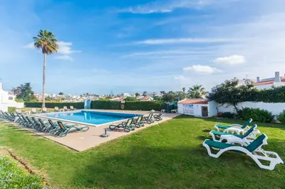 a pool with lounge chairs and a palm tree at Oura Parque Apartamentos Turisticos in Albufeira