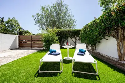 two lounge chairs and a table in the grass at Vilamoura Garden House - Golf & Beach in Vilamoura